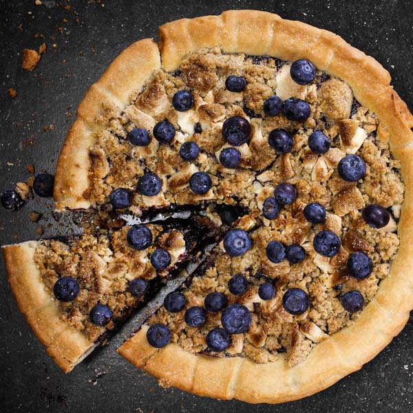 Rund pai med blåbær foran svart bakgrunn