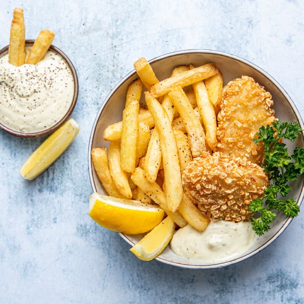 Røstipanert fisk, pommes frites, remulade og sitron i en skål med en liten skål med remulade ved siden av