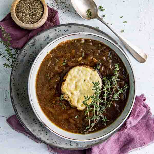 Løksuppe i bolle med en brødskive og fersk timian på toppen